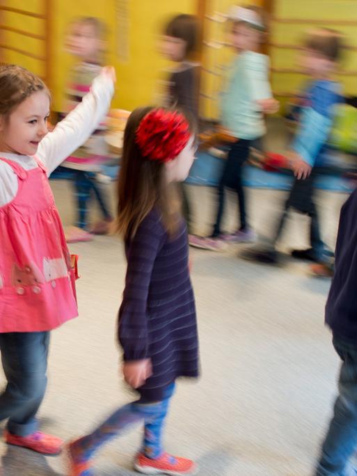 Kinder tanzen während einer Musikstunde durch eine Kindertagesstätte.