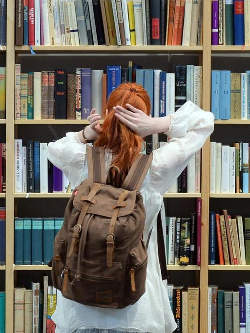 Eine Frau steht vor einem Bücherregal 