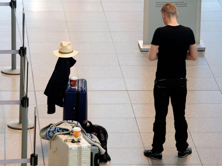 Ein Mann steht am 27.03.2014 während eines Warnstreiks auf dem Flughafen in Stuttgart (Baden-Württemberg) neben seinem Gepäck.