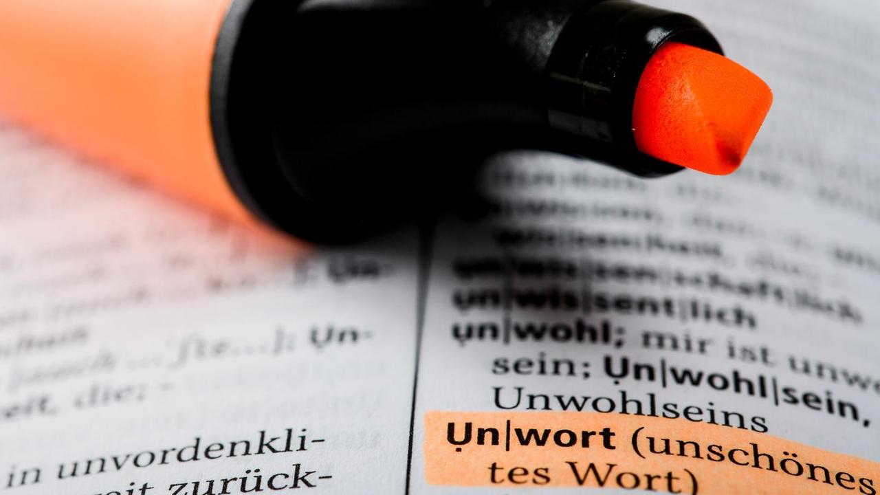Der Begriff "Unwort" ist in einem aufgeschlagenen Wörterbuch mit einem Textmarker markiert.
