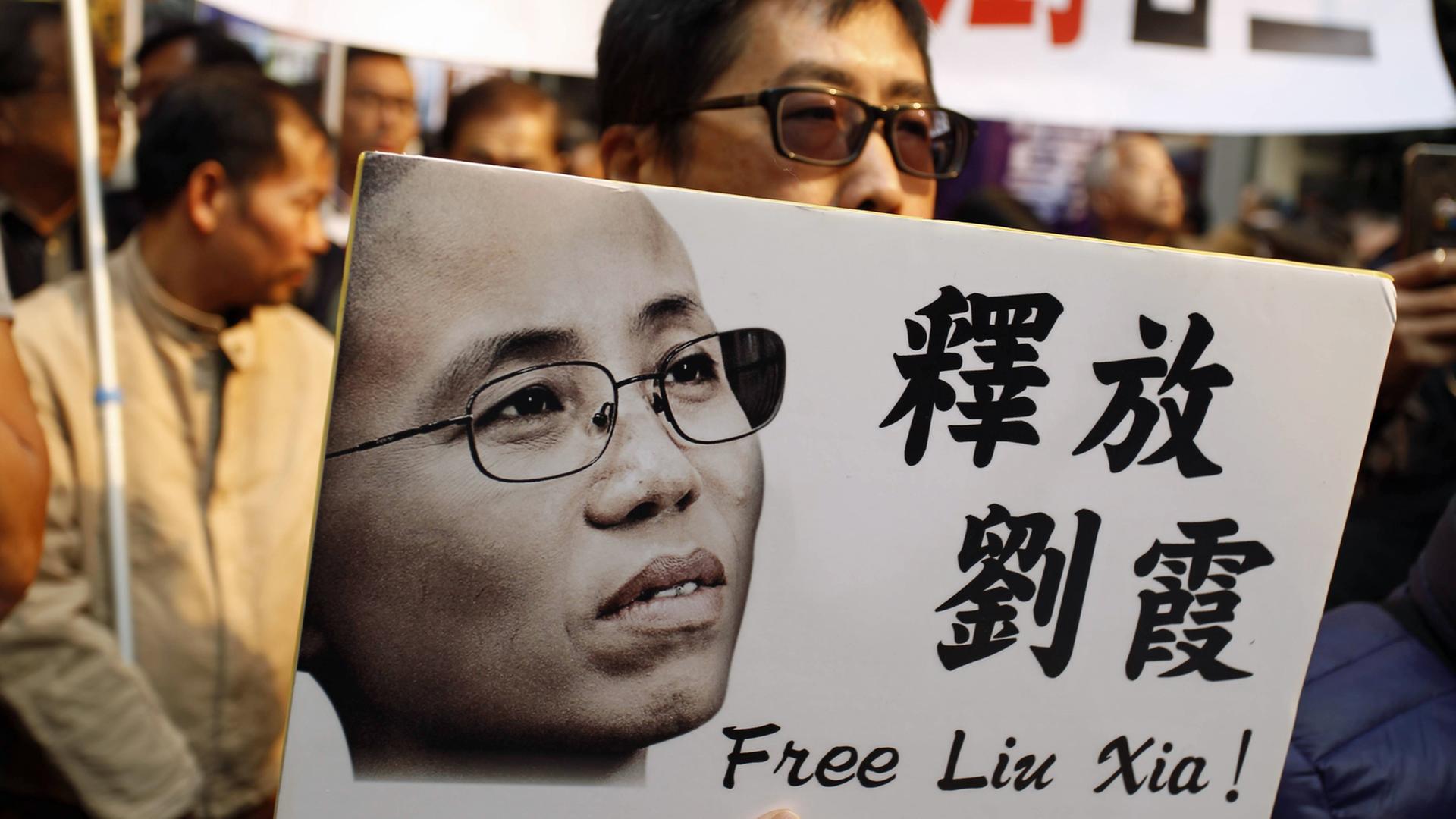  Ein Demonstrant in Hong Kong hält ein Plakat mit einem Bild von Liu Xia, hoch, darauf steht: Free Liu Xia - auf Englisch und Chinesisch.