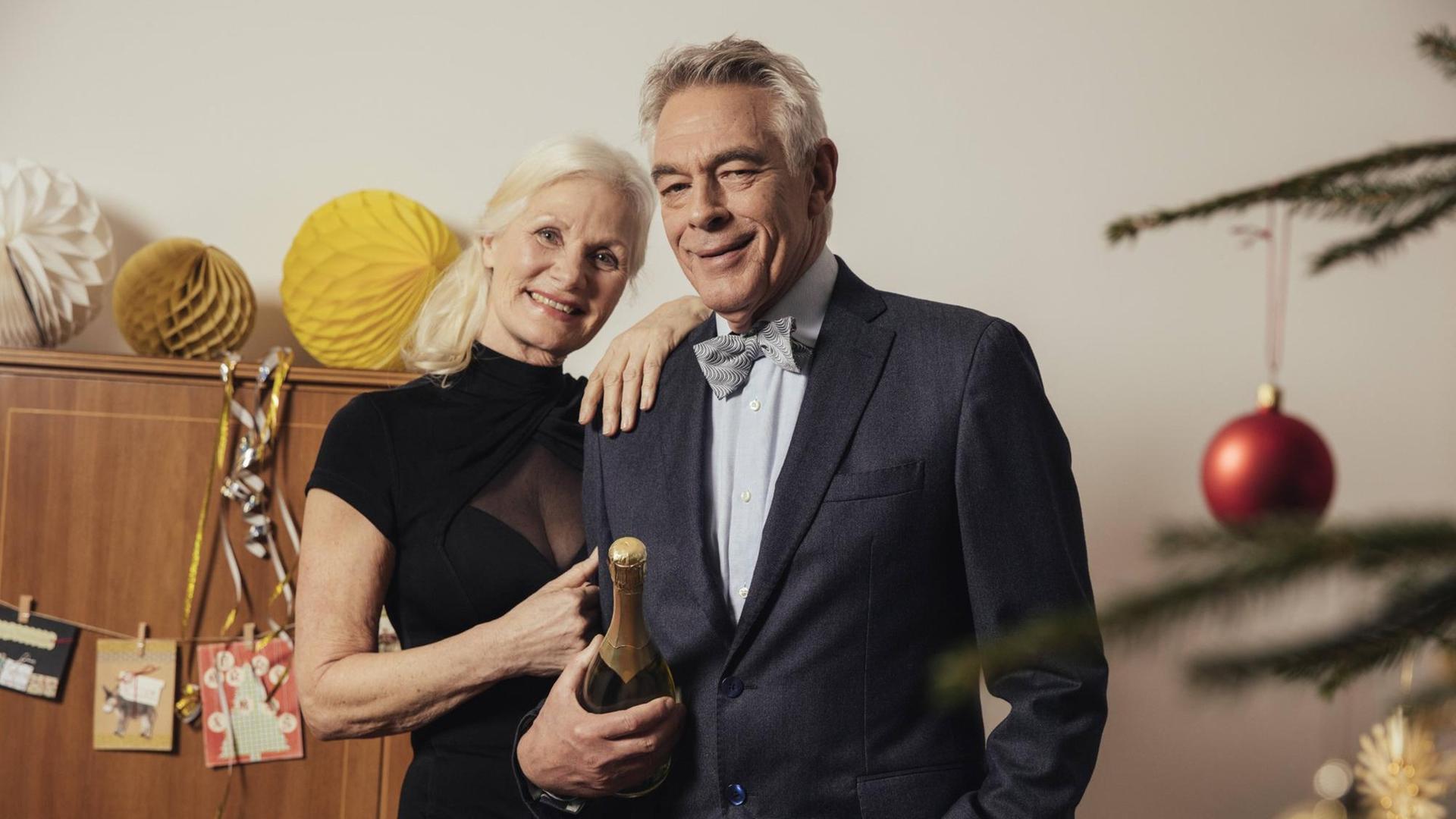 Ein älteres Paar hält am Silvesterabend eine Flasche Champagner in der Hand