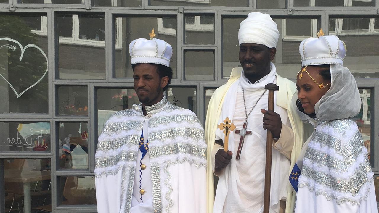 Das Brautpaar, hier vor der Kirche mit Pfarrer Msgun Tamzgi, trägt traditionelle Umhänge.