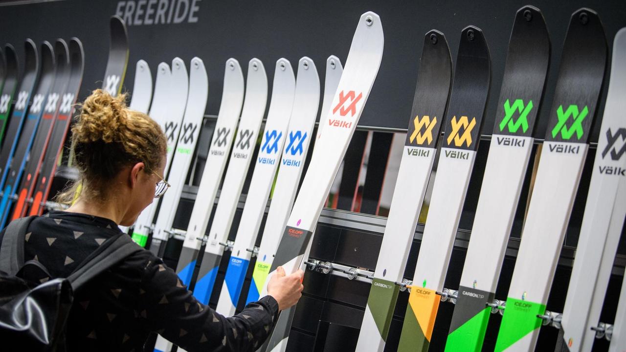 Eine Messebesucherin betrachtet auf der Sportartikelmesse Ispo in München Ski am Stand von Völkl. Auf der Ispo zeigen Aussteller ihre neuesten Sportprodukte.