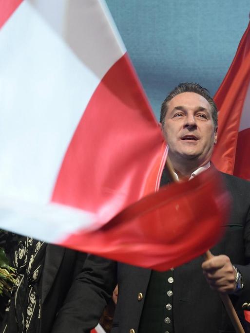 Heinz-Christian Strache schwenkt eine große österreichische Fahne auf einer Bühne.