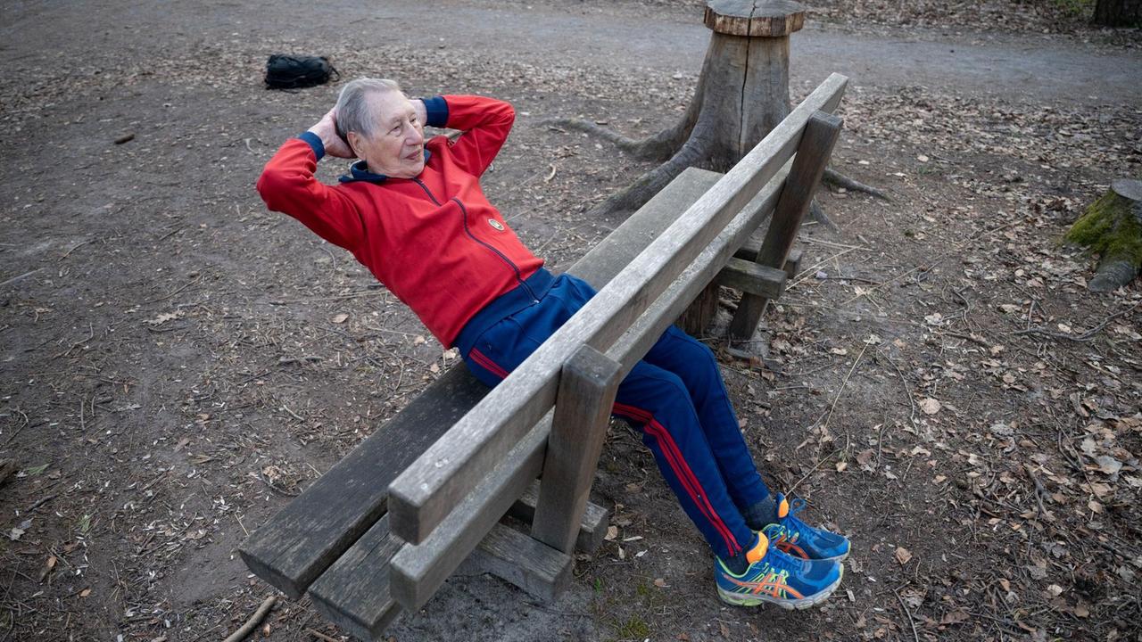 Ein alter Mann macht Sit-ups auf einer Bank.