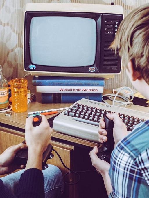 Zwei Jugendliche spielen mit Joysticks an einem Heimcomputer der 80er Jahre, mit Joystick, C64 und russischem Schwarzweißfernseher (nachgestellte Filmszene)