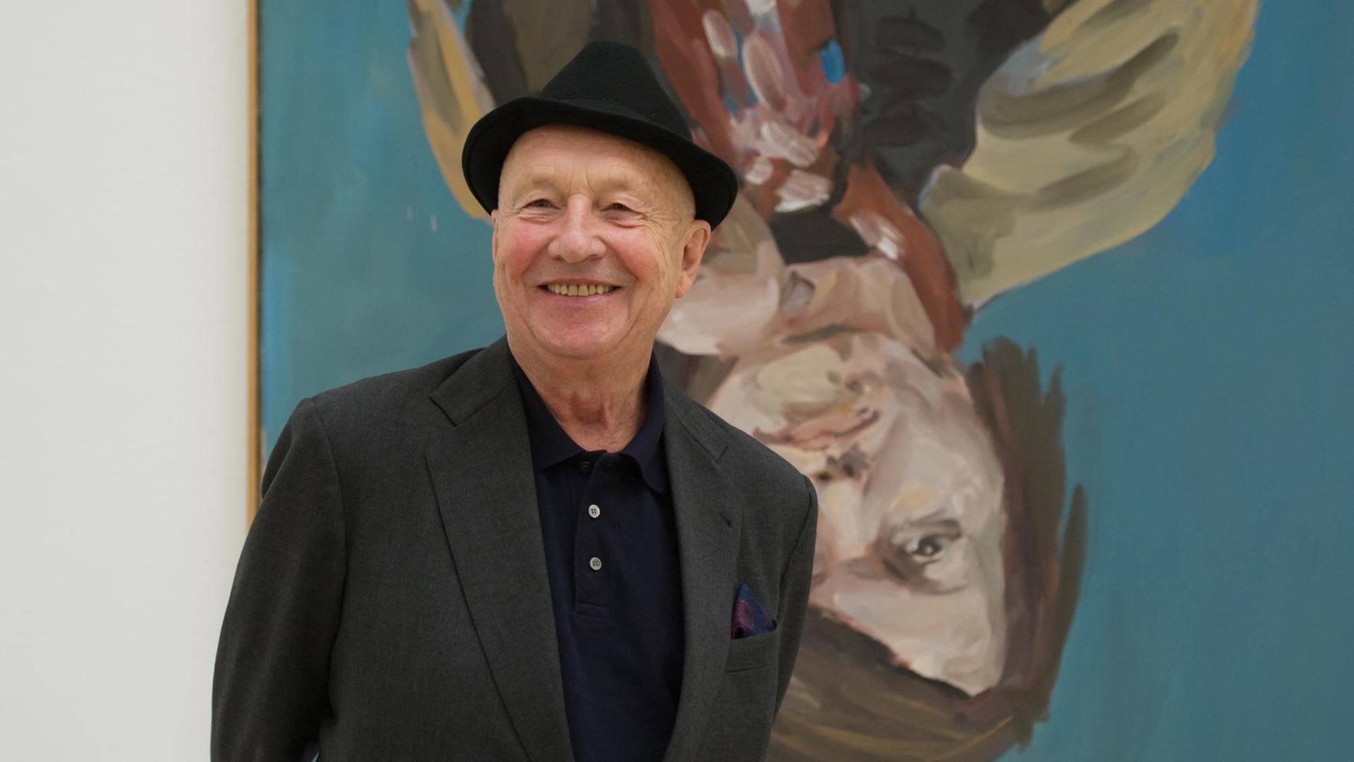 Der Künstler Georg Baselitz steht vor einem Porträt seiner Frau.