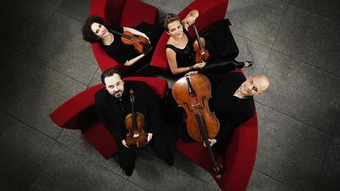 Die Musiker des Artemis Quartett sitzen mit ihren Instrumenten roten Sesseln und blicken nach oben, Bild aufgenommen in Vogelperspektive