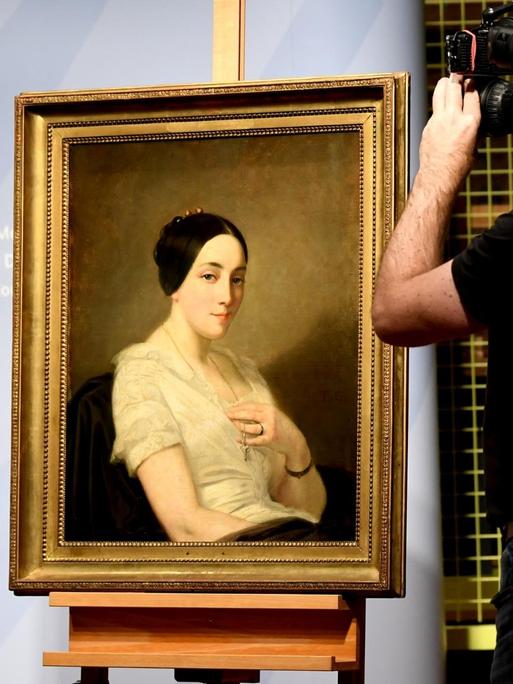 Journalisten filmen das Bild "Porträt einer sitzenden jungen Frau / Portrait de jeune femme assise" des Künstlers Thomas Couture. Das Gemälde aus dem Kunstfund Gurlitt, wurde als NS-Raubkunst identifiziert und an die Nachkommen zurückgegeben.