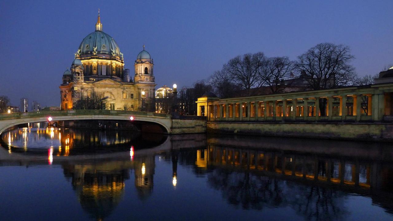 Der Berliner Dom spiegelt sich im Wasser der Spree bei nächtlicher Beleuchtung.