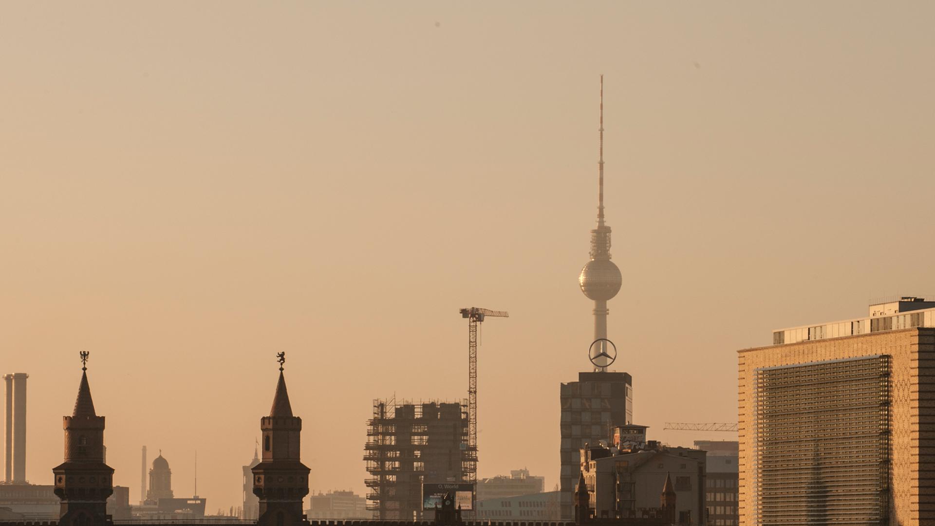 Die Skyline hebt sich in Berlin im Licht der untergehenden Sonne ab. Im Vordergrund die Oberbaumbrücke, dahinter der Fernsehturm.
