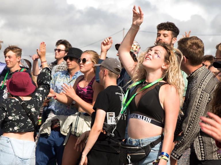Junge Leute tanzen und hören Musik auf einem Festival.