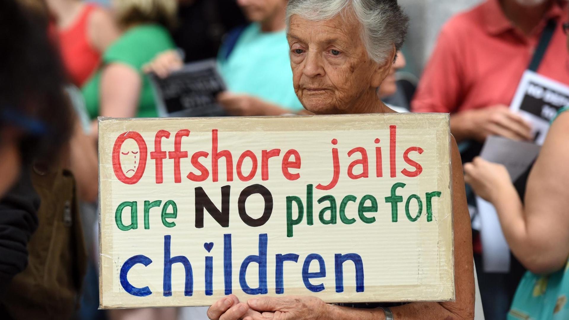 Eine Frau bei einem Prostest in Brisbane/Australien. Sie hält ein Schild mit der Aufschrift: "Übersee-Gefängnisse sind kein Ort für Kinder" und protestiert damit gegen die Flüchtlingslager der australischen Regierung im Pazifik.