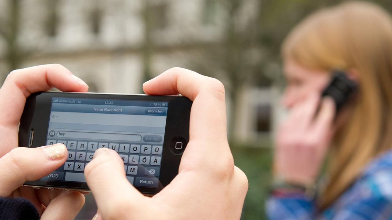 Schüler schreiben SMS und telefonieren am 22.04.2013 auf einem Schulhof in Braunschweig (Niedersachsen).