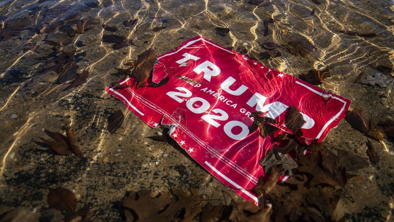 Ein rotes Wahlkampfplakat "Trump 2020" liegt zerfleddert im Wasser vor dem Kapitol Gebäude in Washington D.C., 9.1.2021.