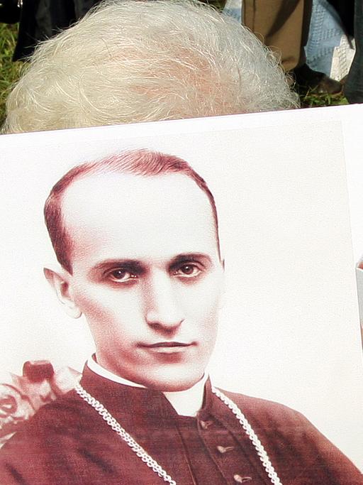 Eine kroatische Frau hält ein Plakat: Zu sehen sind der katholische kroatische Bischof Alojzije Stepinac und Papst Johannes Paul II.; Aufnahme vom Juni 2015