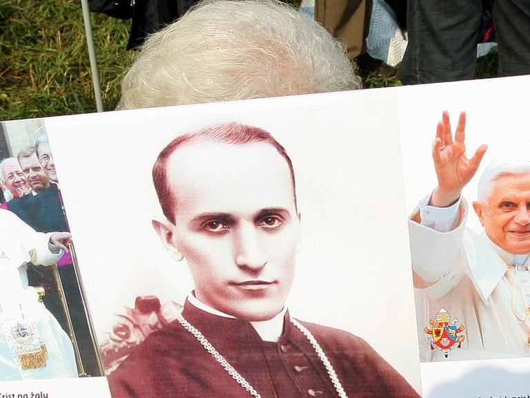 Eine kroatische Frau hält ein Plakat: Zu sehen sind der katholische kroatische Bischof Alojzije Stepinac und Papst Johannes Paul II.; Aufnahme vom Juni 2015