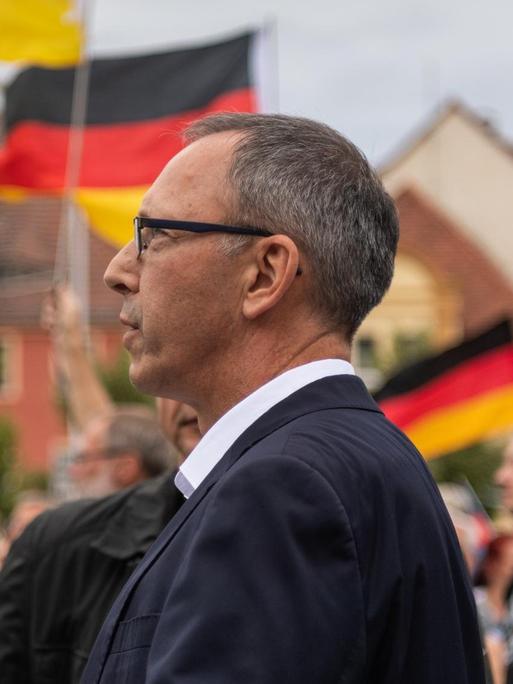 Das Foto zeigt Jörg Urban, Spitzenkandidat der AfD in Sachsen, vor Deutschland-Fahnen.