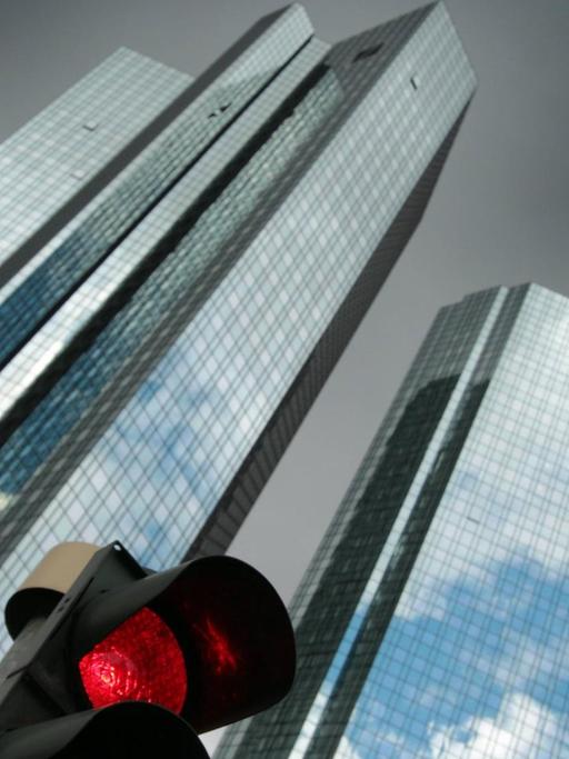 Eine rote Verkehrsampel vor der Zentrale des Unternehmens mit schwarzen Regenwolken im Bankenviertel in Frankfurt am Main.