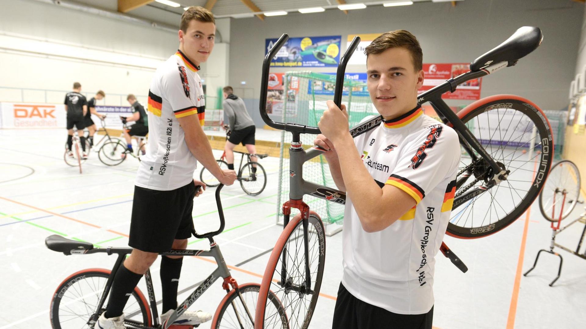 Tim und Eric Lehmann aus Großkoschen im südlichen Brandenburg sind Jugend-Europameister im Radball. Hier halten sie ihre Räder in die Kamera in der Halle.