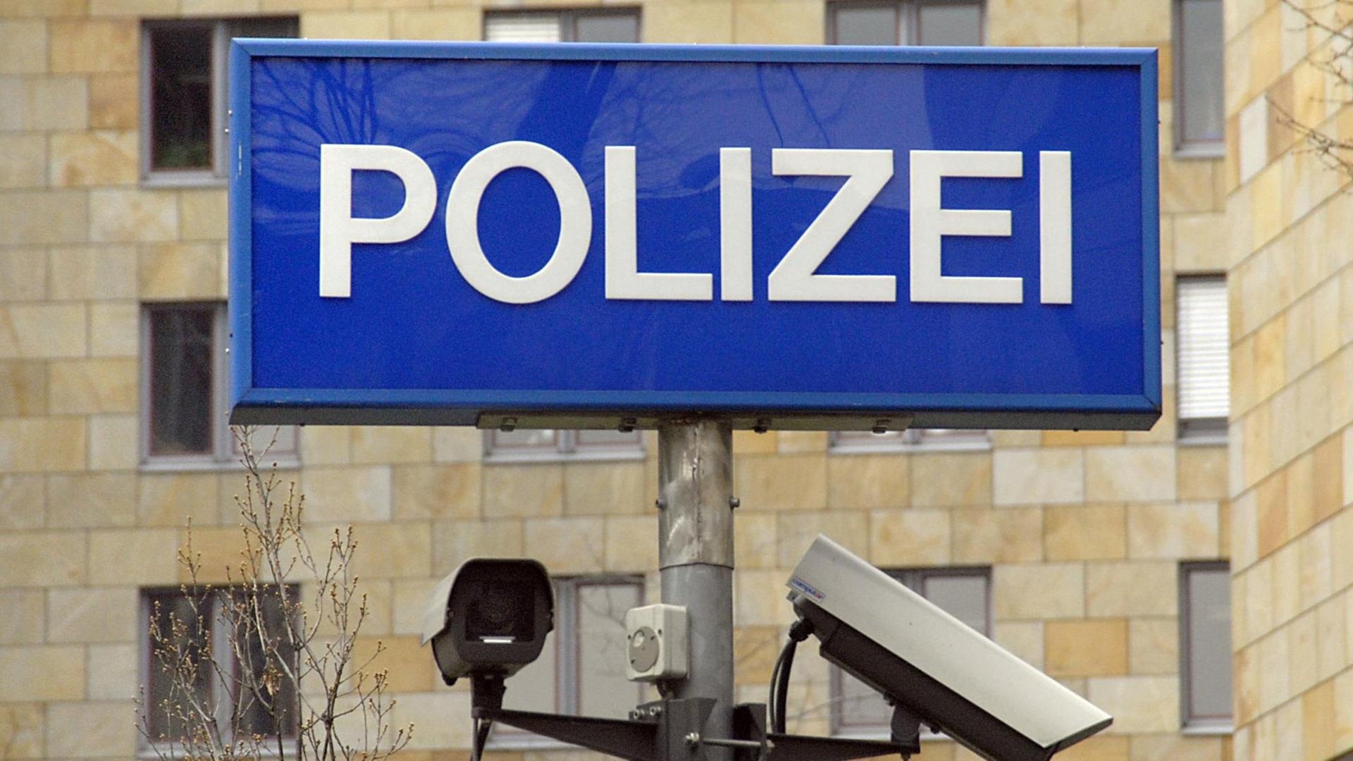 Zwei Überwachungskameras an einem Mast unter einer Leuchthinweistafel mit dem Schriftzug "Polizei" im Behördenzentrum Frankfurt am Main
