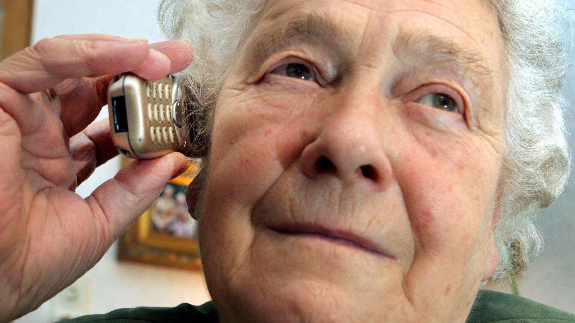Eine 80-jährige Frau telefoniert am 12.02.2005 in ihrem Haus in Bochum mit einem Handy.