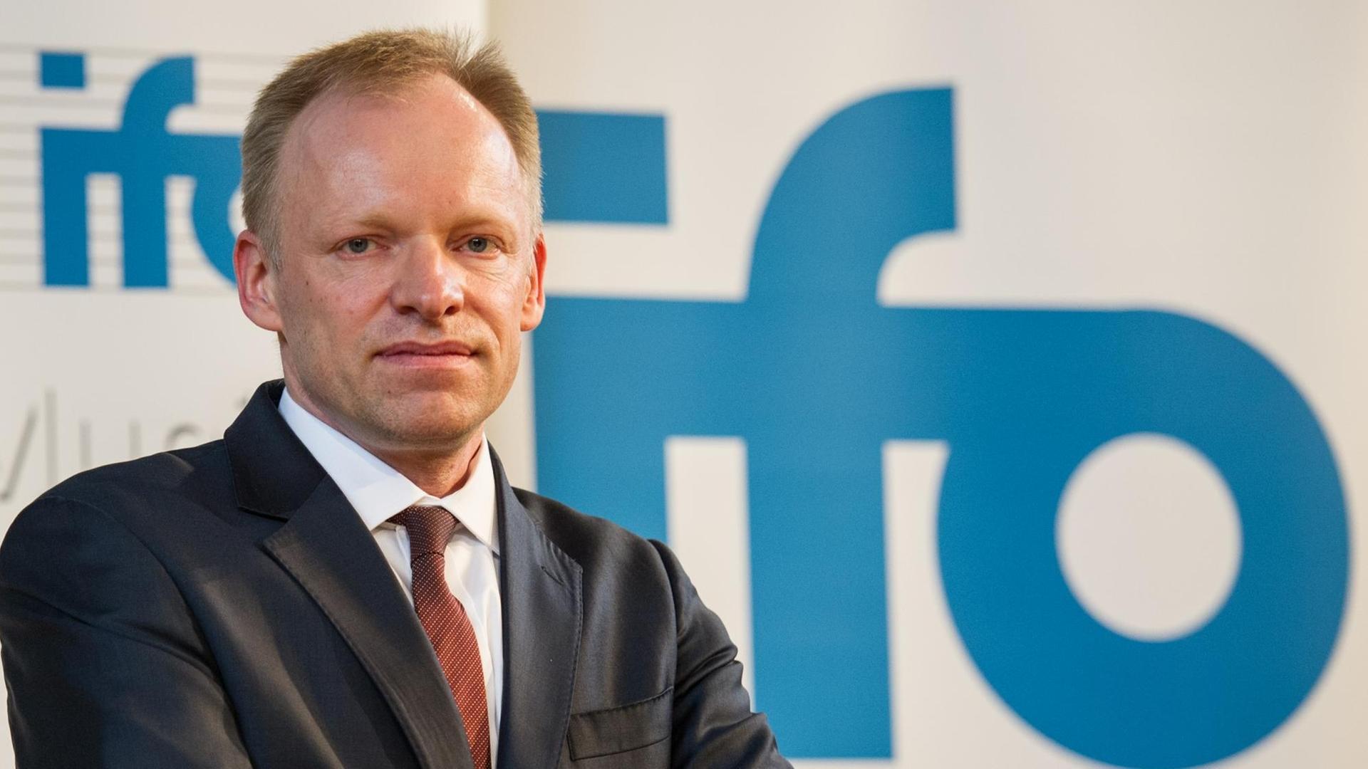 Der Präsident des ifo Instituts, Clemens Fuest, posiert vor einem Schild mit der Aufschrift "ifo".