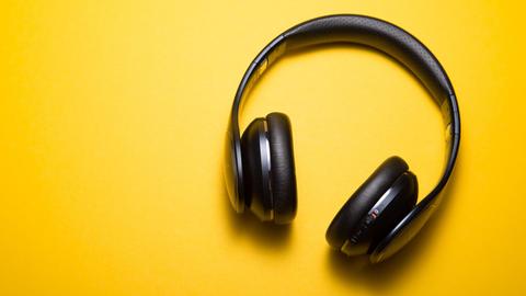 Ein Paar schwarze Over-Ear-Kopfhörer auf gelbem Grund