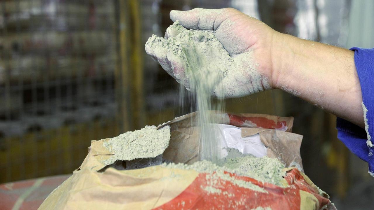 Ein Arbeiter lässt Zement aus dem Zementwerk Lengerich des Unternehmens Dyckerhoff durch die Hand rieseln