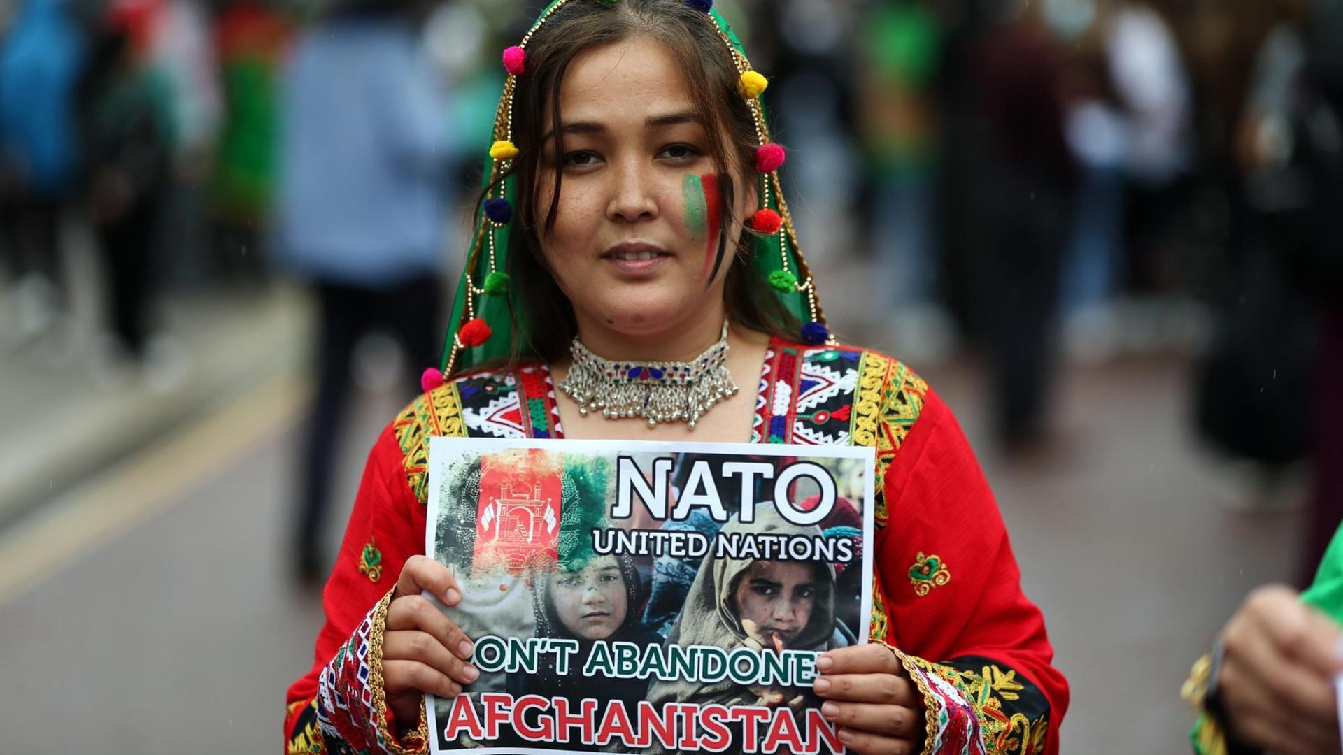 Eine Frau hält ein Schild hoch, auf dem sie die NATO zur Unterstützung für Afghanistan auffordert