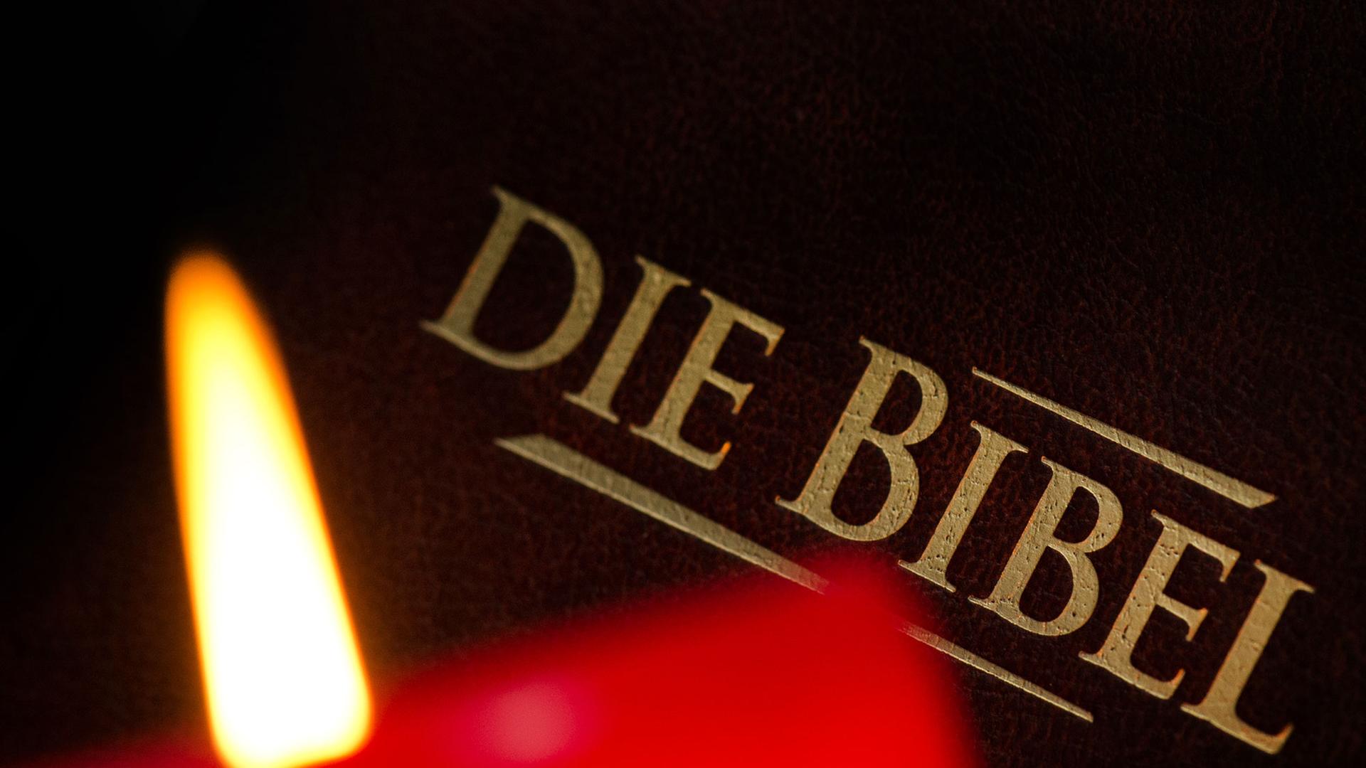 Eine brennende Kerze vor einer Bibel