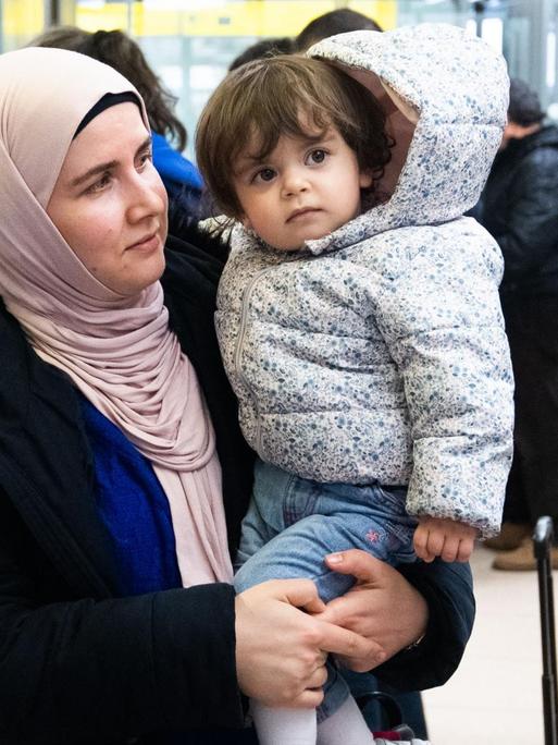 Nach ihrer Ankunft steht eine Frau mit ihrem Kind auf der Arm im Ankunftsbereich vom Flughafen Hannover. Aus der Türkei sind knapp 250 Flüchtlinge am Flughafen Hannover ankommen.