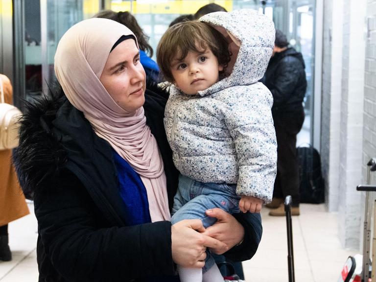 Nach ihrer Ankunft steht eine Frau mit ihrem Kind auf der Arm im Ankunftsbereich vom Flughafen Hannover. Aus der Türkei sind knapp 250 Flüchtlinge am Flughafen Hannover ankommen.