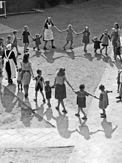 Schwestern tanzen mit den Kindern eines Kinderheims einen Ringeltanz in Frankfurt an der Oder, 1948.