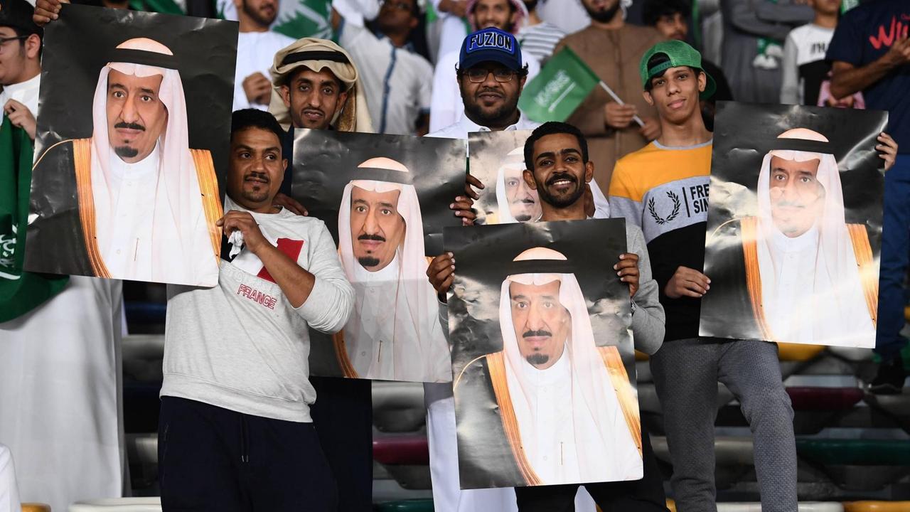 Saudi-arabische Fußball Fans mit Plakaten von König Salman ibn Abd al-Aziz beim Spiel gegen Katar