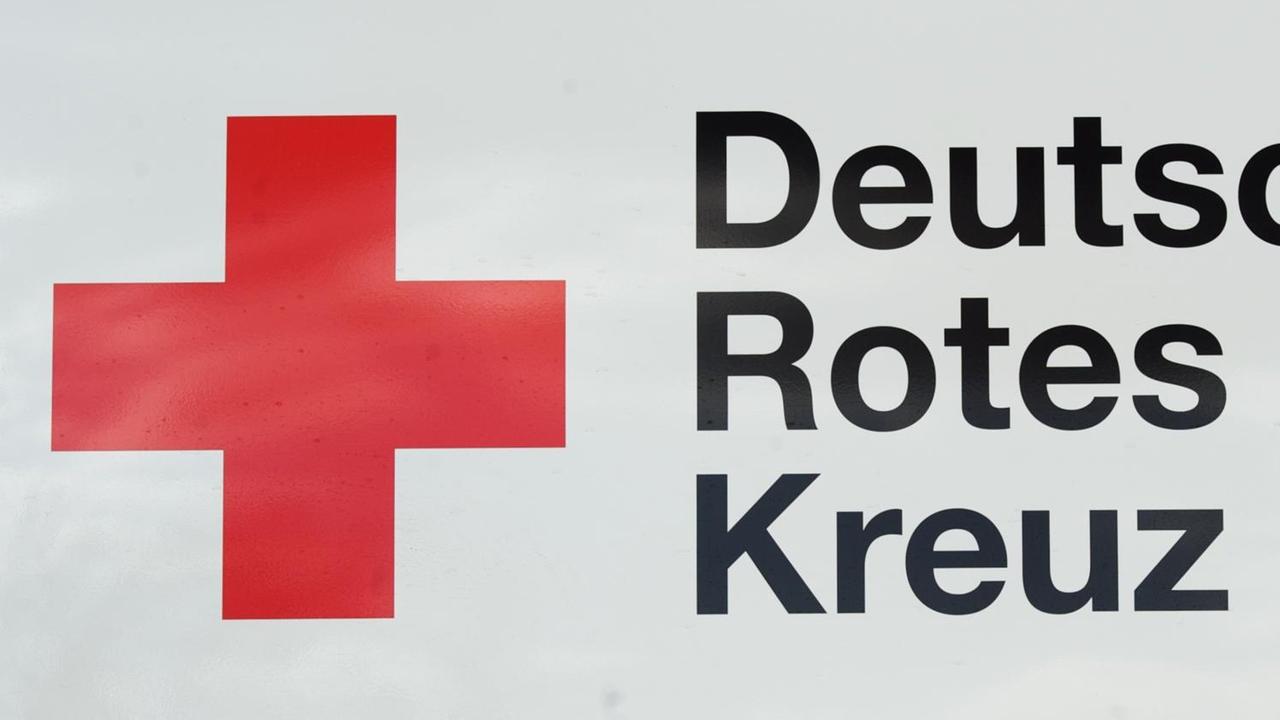Zu sehen ist ein großes Rotes Kreuz auf einem weißen Hintergrund mit dem dazu gehörigen schwarzen Schriftzug "Deutsches Rotes Kreuz". Zu sehen ist ein großes Rotes Kreuz auf einem weißen Hintergrund mit dem dazu gehörigen schwarzen Schriftzug "Deutsches Rotes Kreuz".