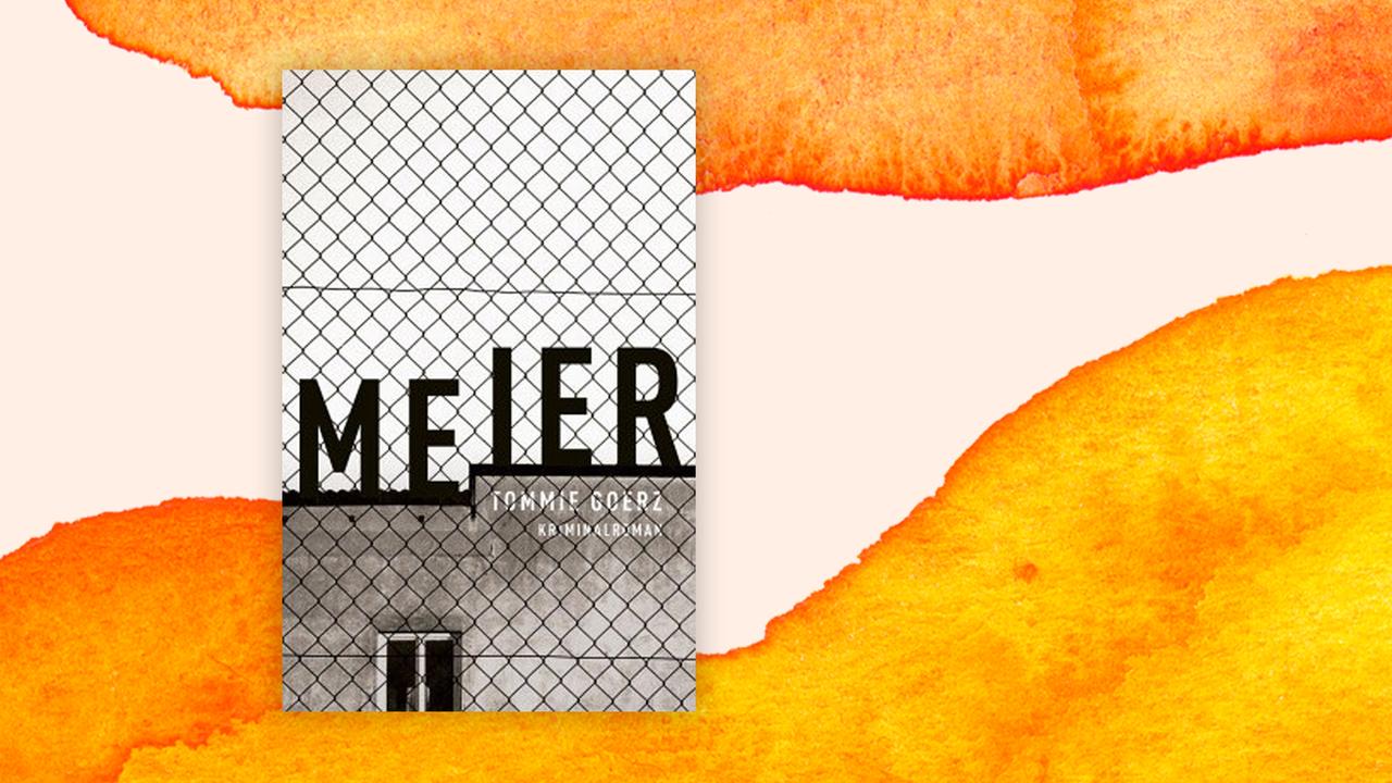 Das Cover von Tommie Goerz' Buch "Meier" auf orange-weißem Hintergrund. Auf einem Flachdachgebäude steht auf dem Cover in schwarzen Großbuchstaben "Meier". im Vordergrund ist auf ganzer Höhe des Covers ein Drahtzaun zu sehen.