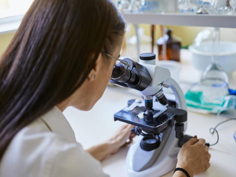 Young woman using microscope in laboratory model released Symbolfoto property released PUBLICATIONxINxGERxSUIxAUTxHUNxONLY ZEDF01018