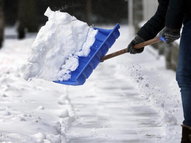 Mit einer Schneeschaufel befreit am 11.03.2013 in Berlin eine Anwohnerin den Gehsteig von der frisch gefallenen weißen Pracht. Nach Angaben der Meteorologen wird sich der Wintereinbruch auch in den kommenden Tagen mit weiteren Schneefällen und kalten Temperatuten fortsetzen.