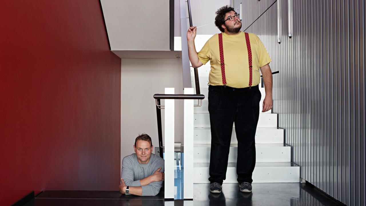 Devid Striesow und Axel Ranisch stehen im Treppenhaus von Deutschlandfunk Kultur.