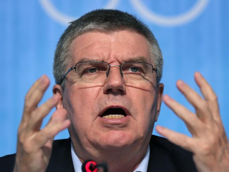 Sie sehen IOC-Präsident Bach, er gestikuliert mit den Händen.
