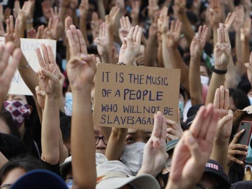 Proteste in Bangkok, Thailand. Die Menschen halten die Hände mit dem Drei-Finger-Gruß in die Luft, 16. August 2020.