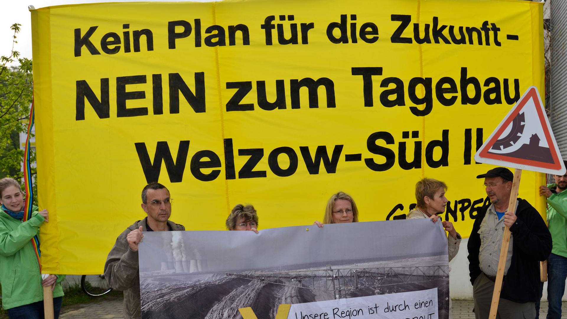 Blick auf Braunkohlegegner und Greenpeace-Aktivisten, die mit einem Transparent mit der Aufschrift "Kein Plan für die Zukunft - Nein zum Tagebau Welzow-Süd II" vor der Sitzung des Braunkohlenausschusses in Cottbus (Brandenburg) protestieren.