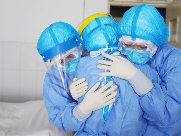 Drei Krankenpflegerinnen umarmen sich.