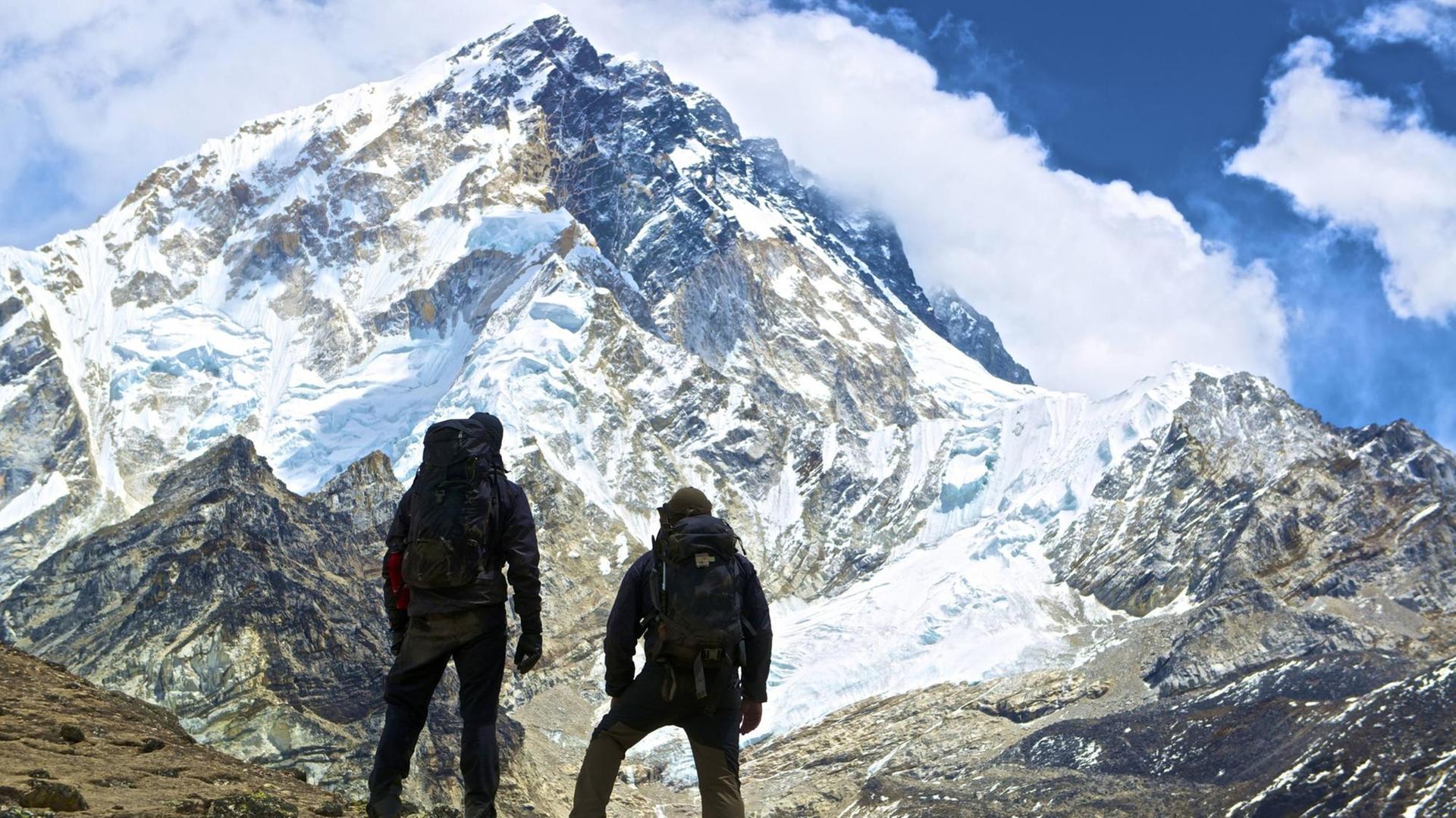 Zwei Bergsteiger blicken auf den Ama Dablam im Himalaya.