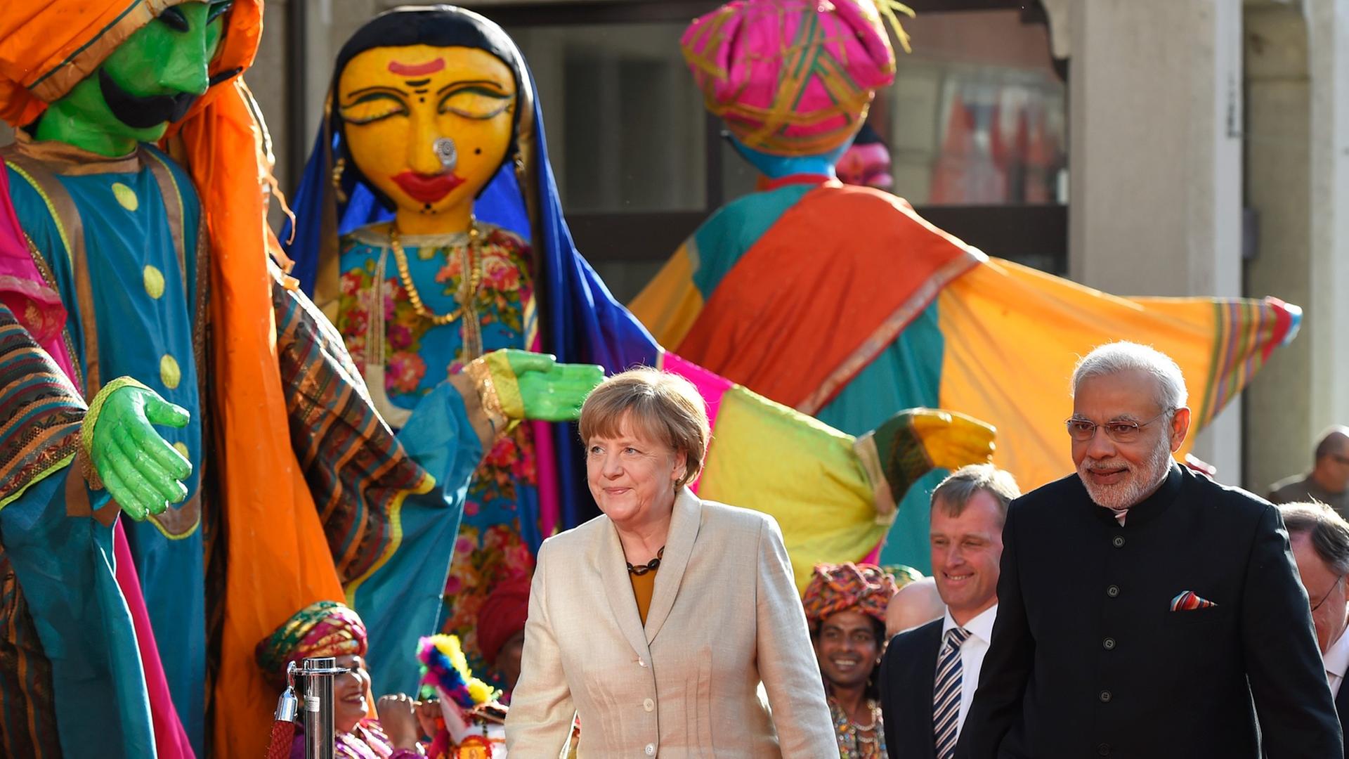 Merkel und Modi stehen bei der Eröffnung der Messe vor bunten indischen Puppen.