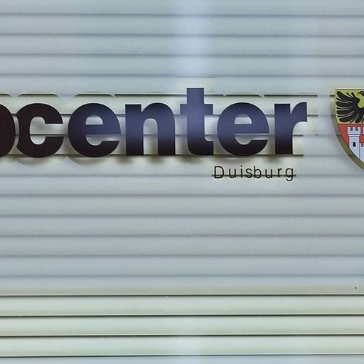 Das Bild zeigt den Schriftzug Jobcenter auf einer Fensterscheibe. 