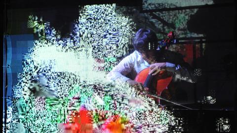 Musiker spielt bei den Donaueschinger Musiktagen 2012 hinter einer Videowand auf einem Cello. 