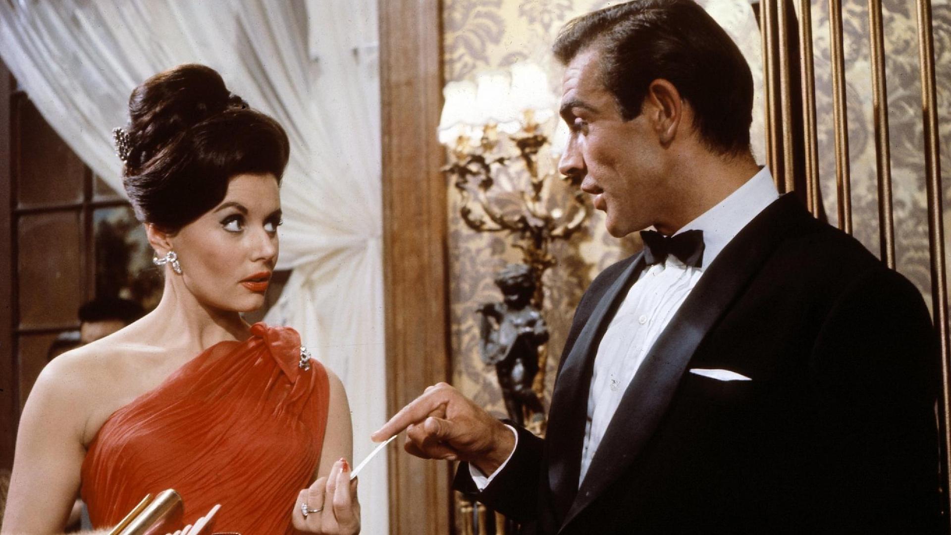 Sean Connery als 007 überreicht Eunice Gaysson als Sylvia in dem britischen Film "James Bond - 007 jagt Dr. No" Casino-Chips.